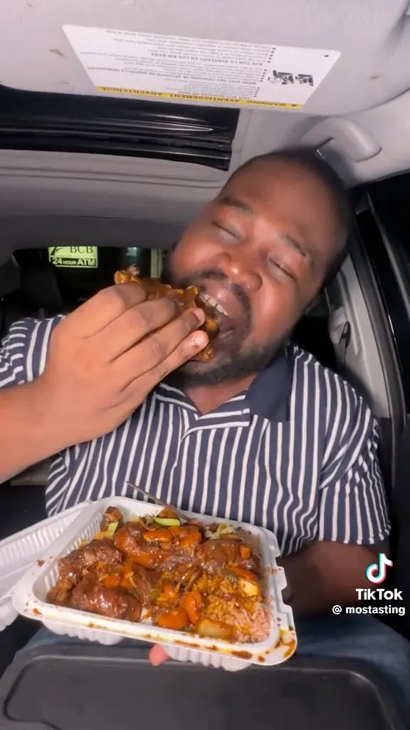 A guest holding a tray of oxtail from Nice and Knuff Jamaican Cuisine